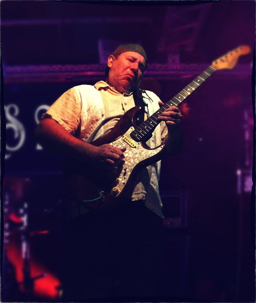 Gordon James playing live under purple stage lights.